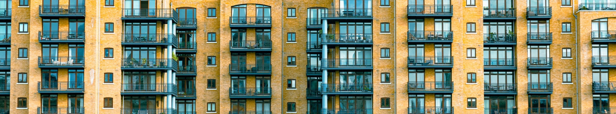 Fenêtres et balcons d’un immeuble dans un cadrage panoramique très étroit.