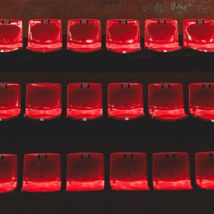 Rangées de sièges rouges formant des alignements réguliers sur un fond sombre.