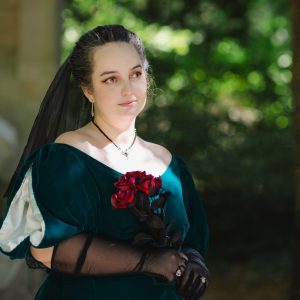 Femme en robe vert foncé avec des roses rouges.